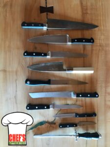 A collection of cooking knives on a rustic wood background