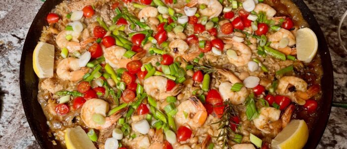 a paella pan of colorful paella with shrimp chicken and sausage and vegetables