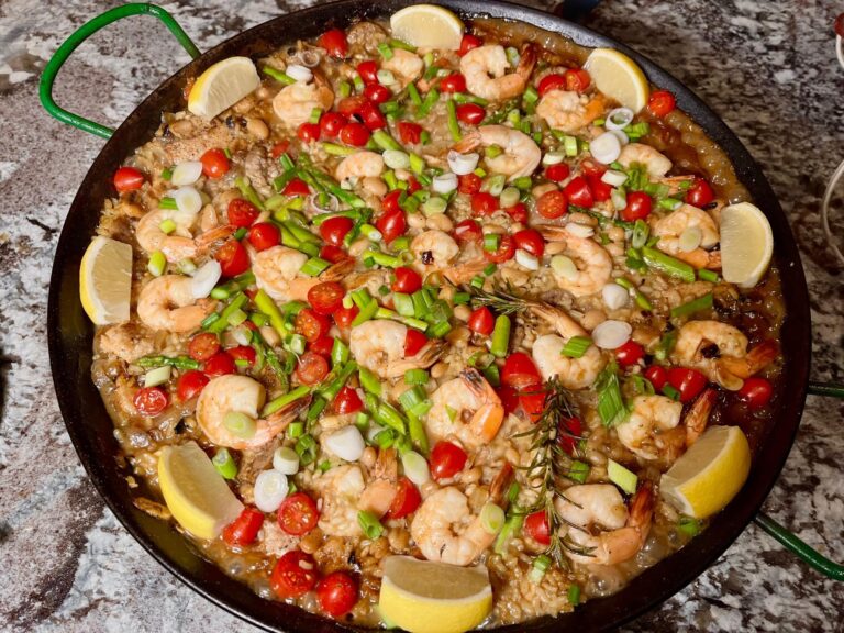 a paella pan of colorful paella with shrimp chicken and sausage and vegetables