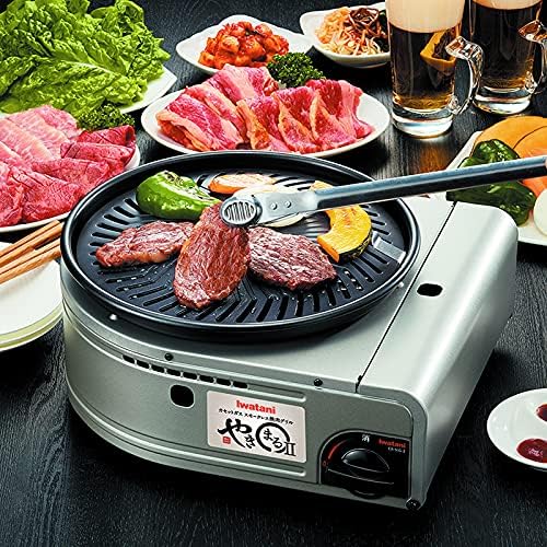 photo of a Yakiniku propane grill showing beef and vegetables in the background, beef being placed on the grill with tongs, and two mugs of beer