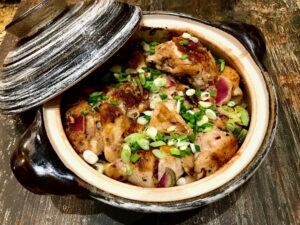a Japanese donabi hotpot full of chicken, vegetables, and broth