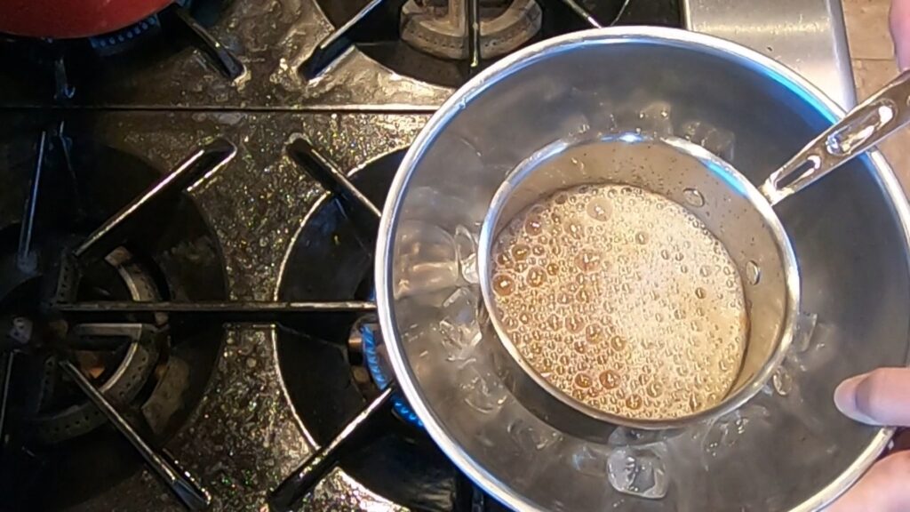 a saucepan of hot melted butter being placed in a bowl of ice