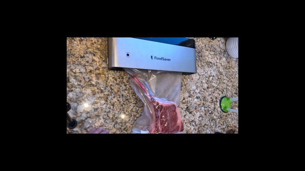 photo of a FoodSaver brand vacuum sealing machine being used to vacuum seal a tomahawk beef steak in a vacuum sealing bag