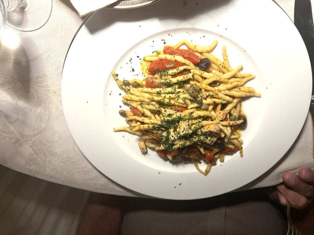 Trofie Amatriciana pasta with tomatoes on a white plate