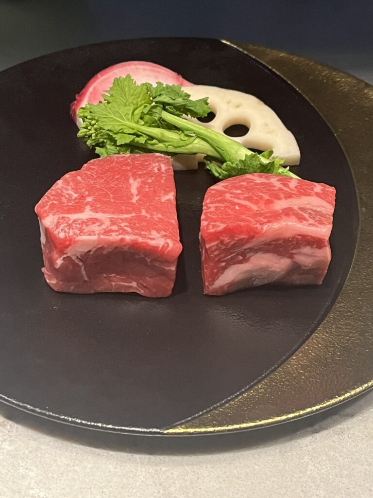two uncooked pieces of Wagyu beef and a few vegetables for garnish