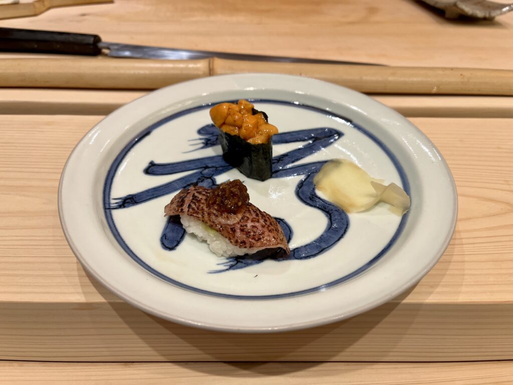 two pieces of sushi on a white plate with a blue design