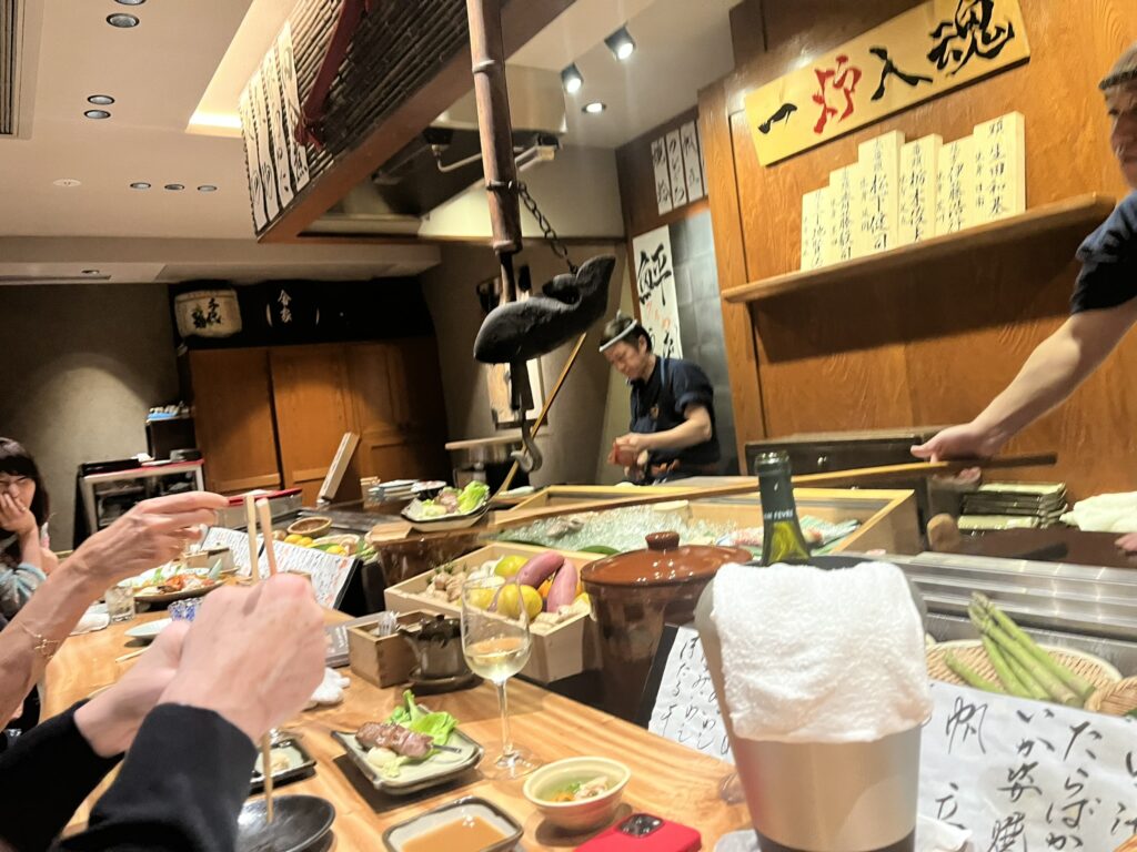 a robata chef handing food to a guest on a long paddle