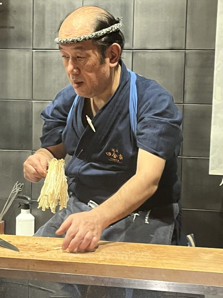 a robata chef preparing enoki mushrooms