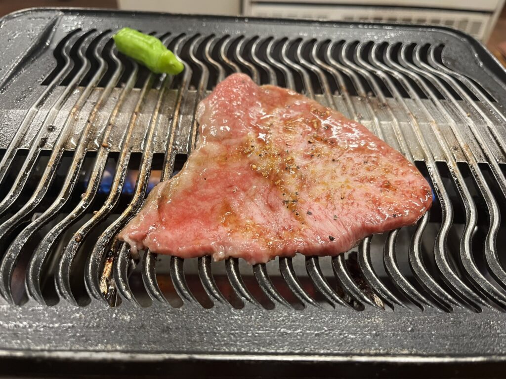 a piece of beef cooking on a Yakiniku grill