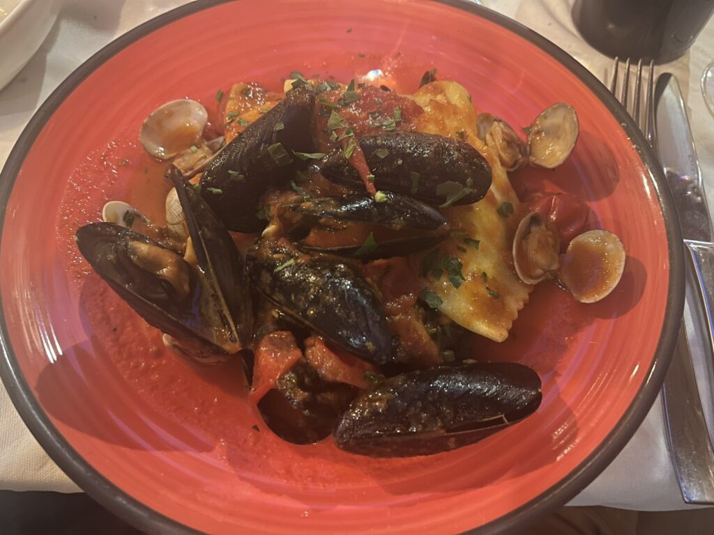 Sea Bass Ravioli with mussels and clams in a red bowl