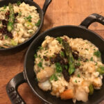 a small iron pot full of risotto rice garnished with an asparagus tip