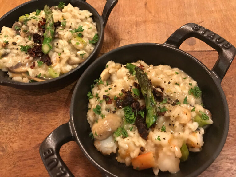 a small iron pot full of risotto rice garnished with an asparagus tip