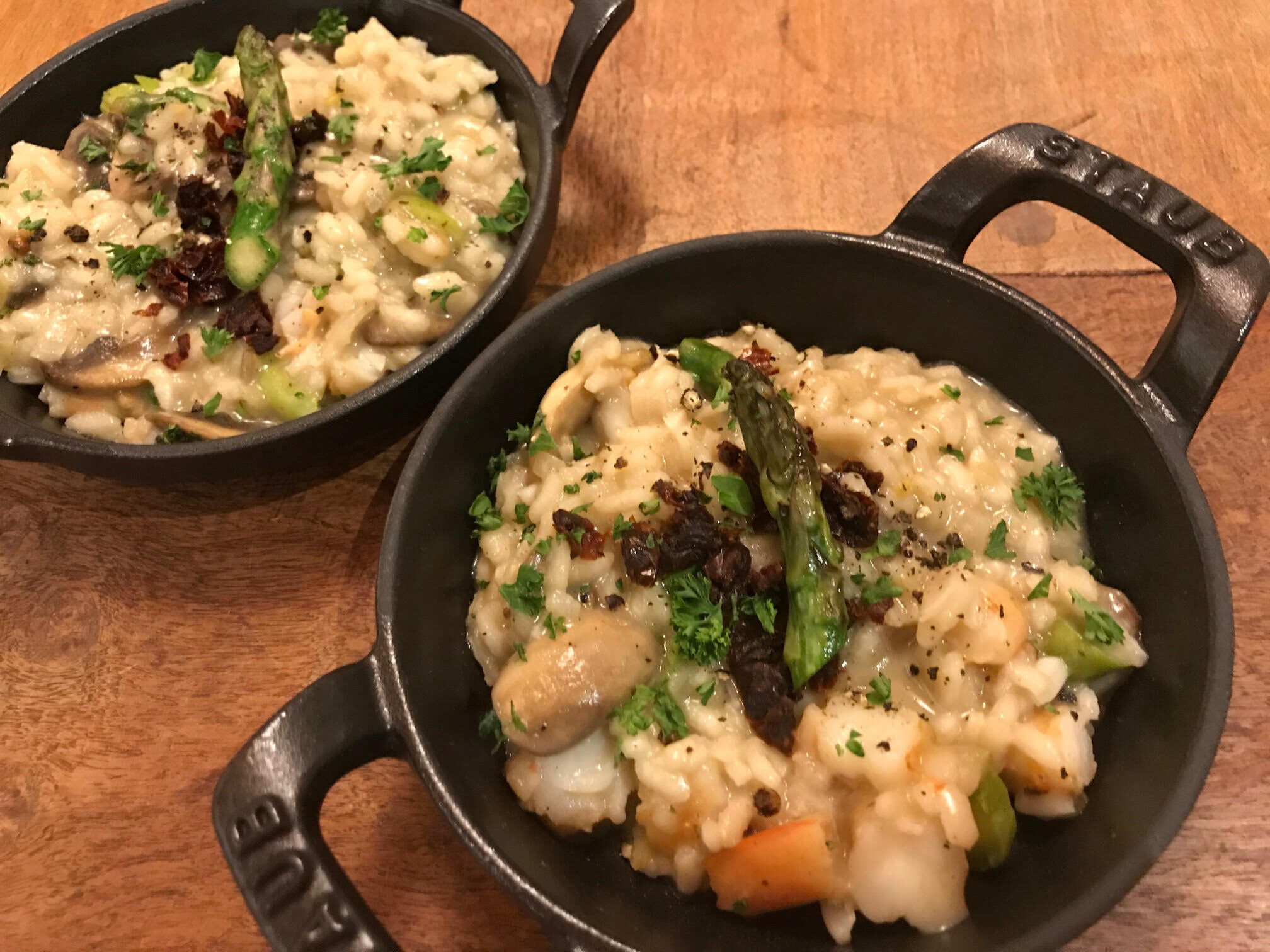 a small iron pot full of risotto rice garnished with an asparagus tip