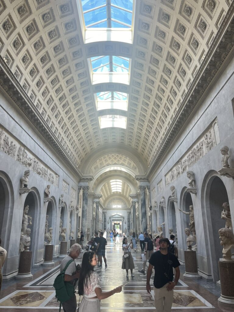 a hallway in The Vatican Museum with statues along both walls