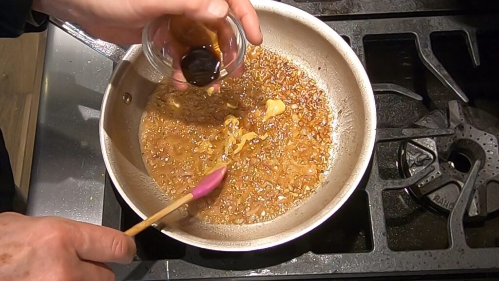 Worcestershire sauce being added to a saute pan with butter, mustard, and shallots
