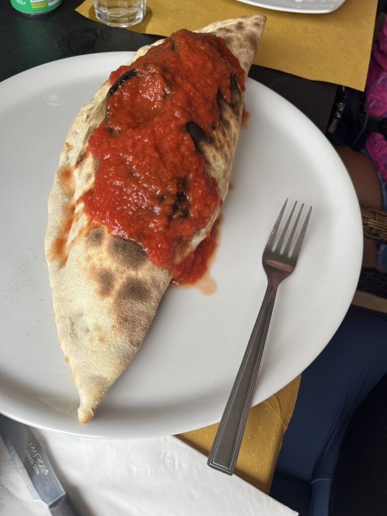 calzone on a white plate with red sauce and a fork