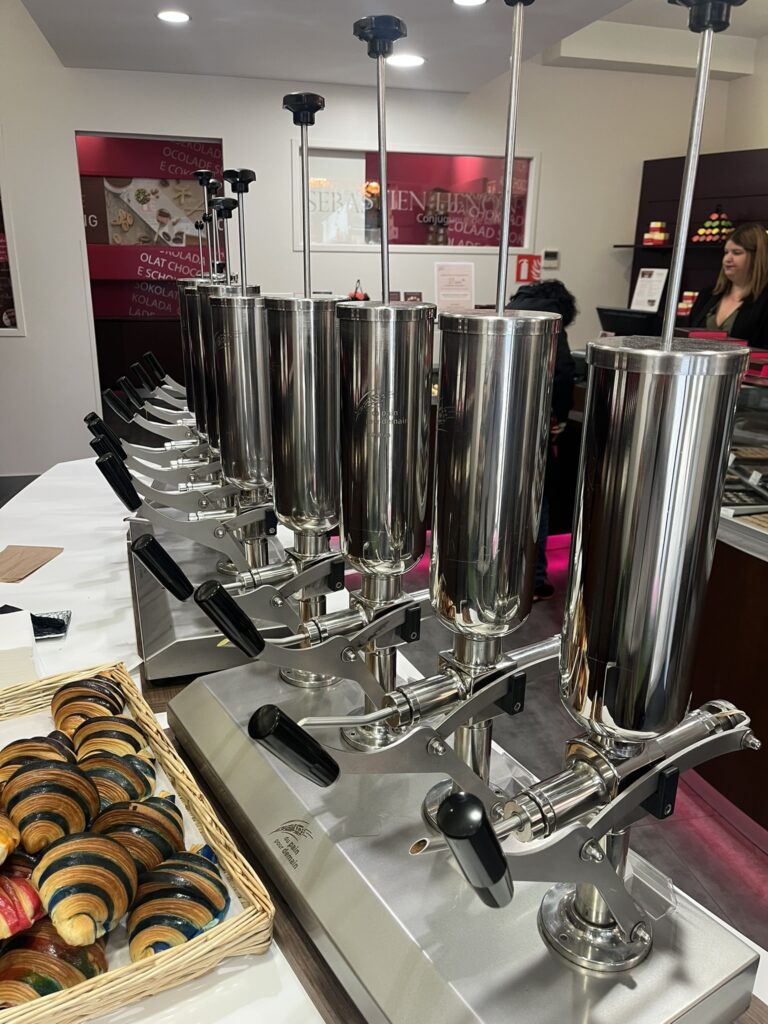a row of machines for injecting flavored cream into croissants, front view