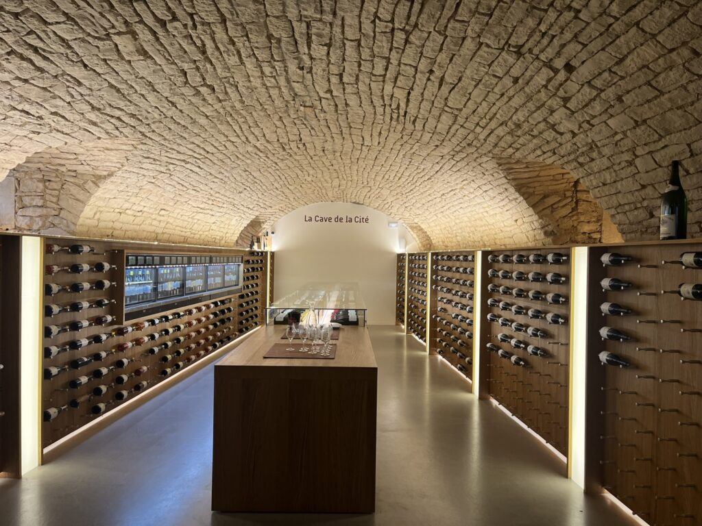 a barrel vaulted cave with a display of wine bottles mounted to walls and wine dispensing machines at La Cave de la Cité in Dijon France