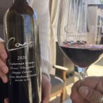 a bottle of Carr wine and a hand holding a glass of wine