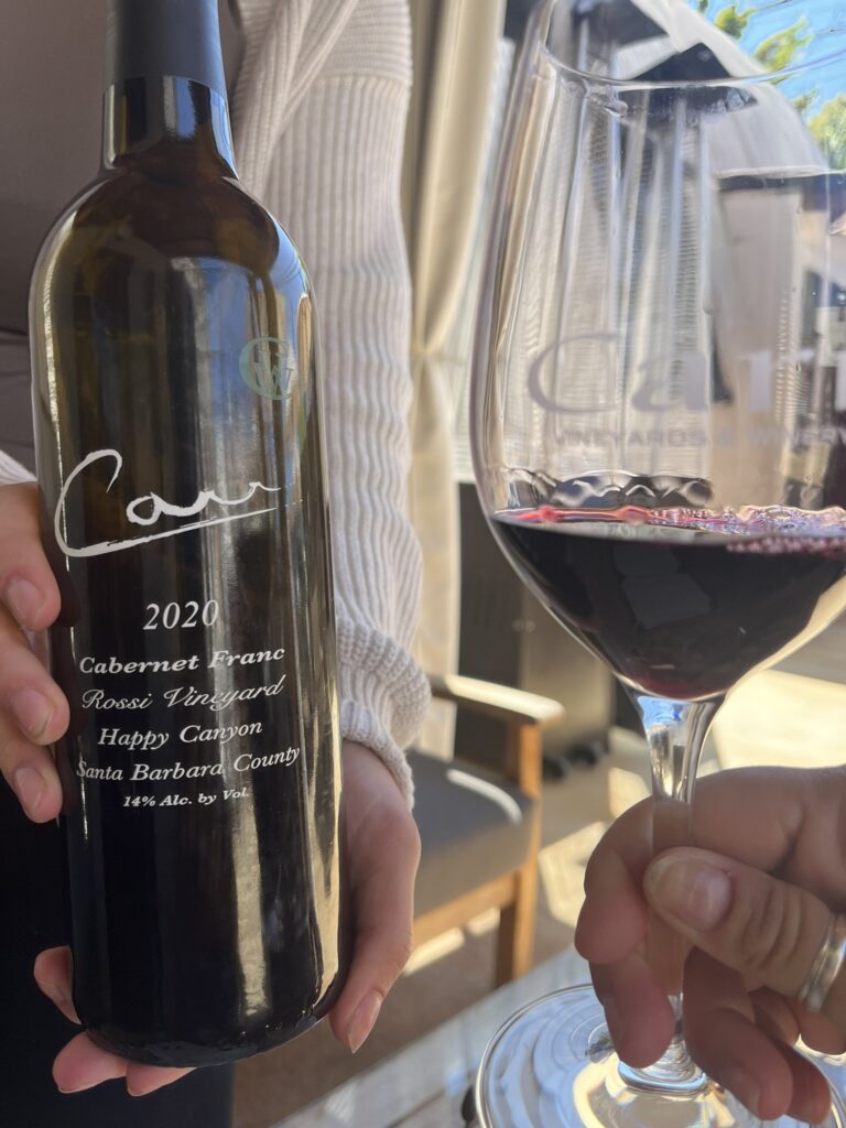 a bottle of Carr wine and a hand holding a glass of wine