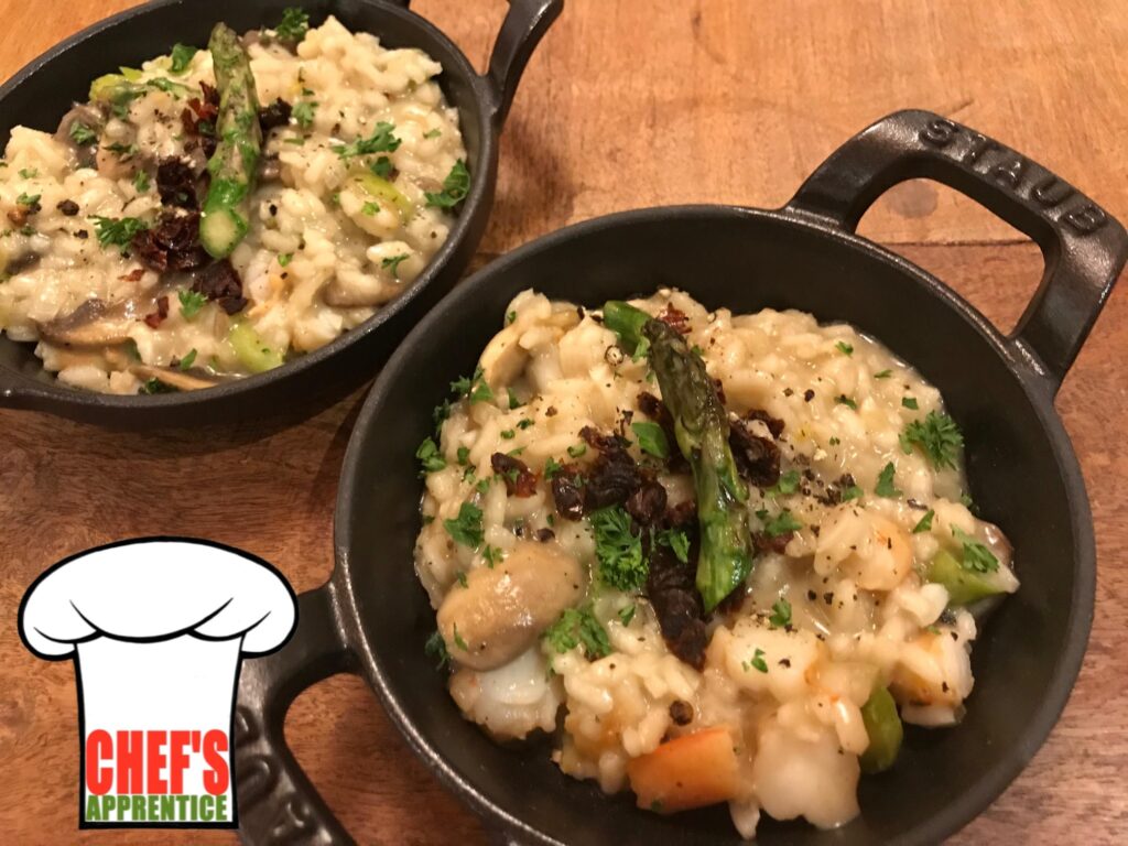 two cast iron dishes of risotto garnished with an asparagus tip